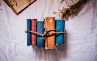 Vintage cloth bound books in blue, red and orange tied with twine on a white sheet