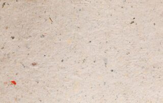 Close-up of recycled paper with visible fiber flecks and a natural, uneven texture