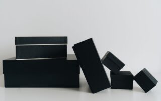 Matte black rigid boxes of different sizes arranged on a white surface