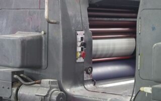 Close-up of rollers inside an offset printing press used for commercial print and packaging